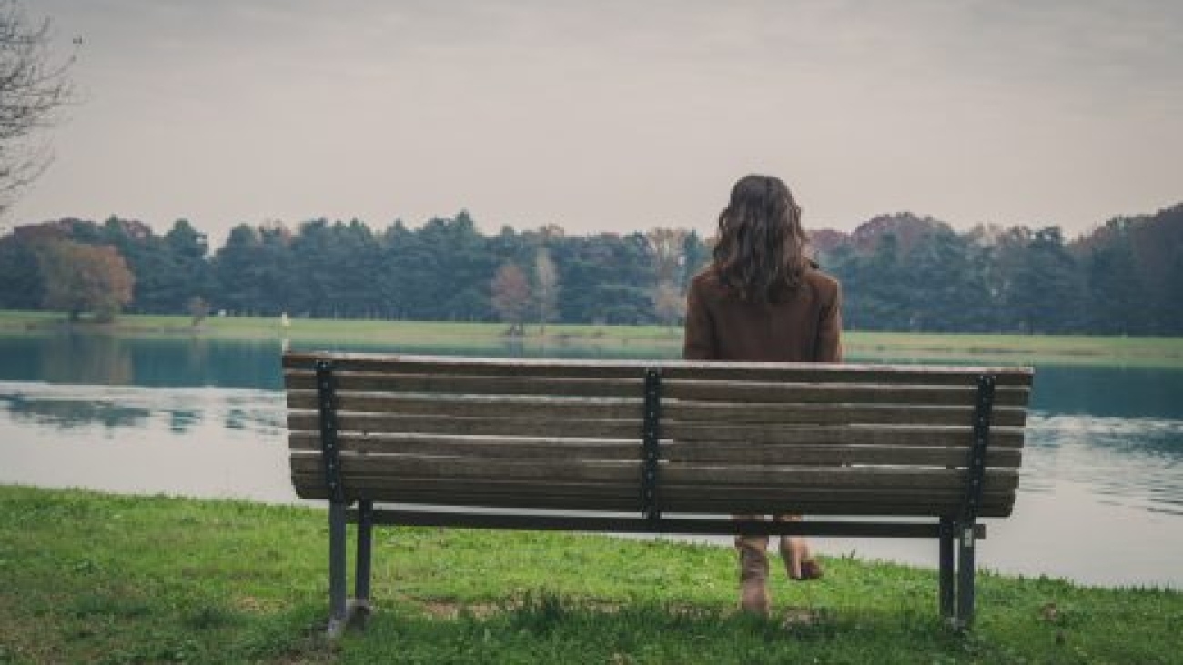 Beautiful young woman with long hair sitting on a bench in a city park