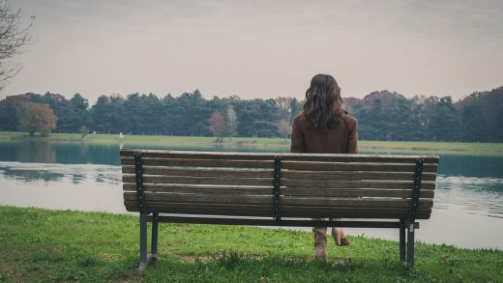 Beautiful young woman with long hair sitting on a bench in a city park