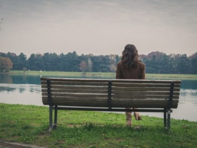 Beautiful young woman with long hair sitting on a bench in a city park