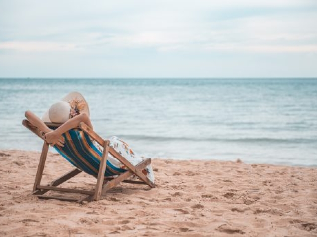 Beautiful young asian woman with hat arm up relaxing on beach chair, Summer happy beach vacation concept.