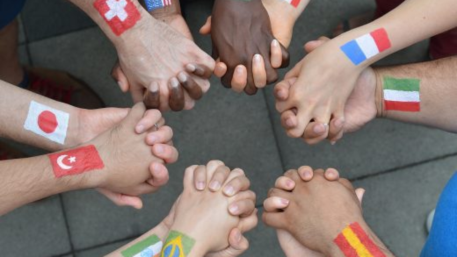 International brothers and sisters standing in a circle together and holding hands as a symbol for peace and the world community