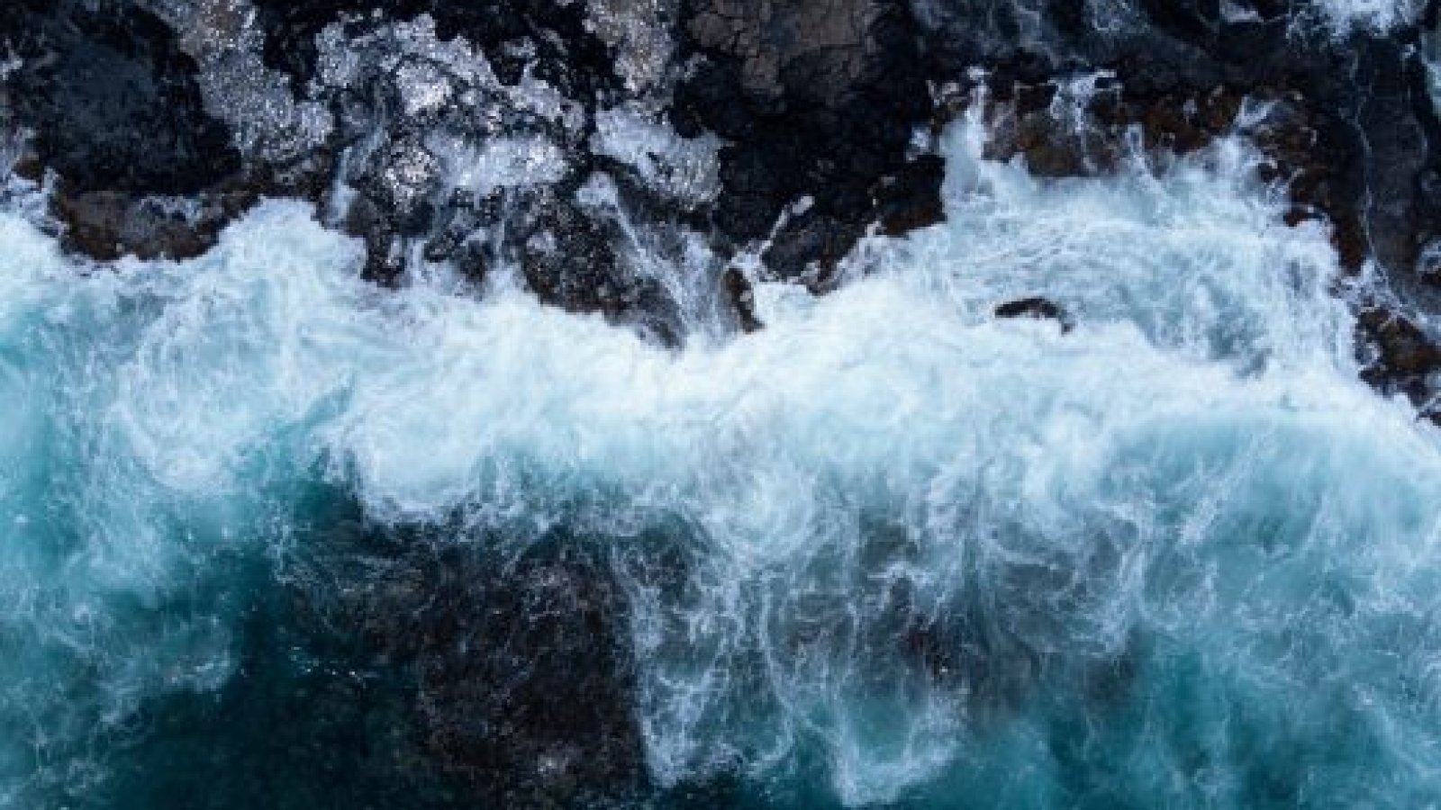 Top Down Aerial View Waves Crashing on Rocks. High quality photo. Near Spitting Cave on Oahu, Hawaii. Shot on DJI Air 2s Drone.
