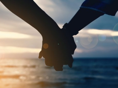 Cropped Hands Of Couple At Beach Against Cloudy Sky During Sunset