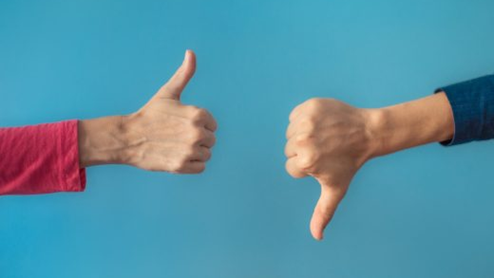 Two people making hand sign thumbs up and thumbs down.