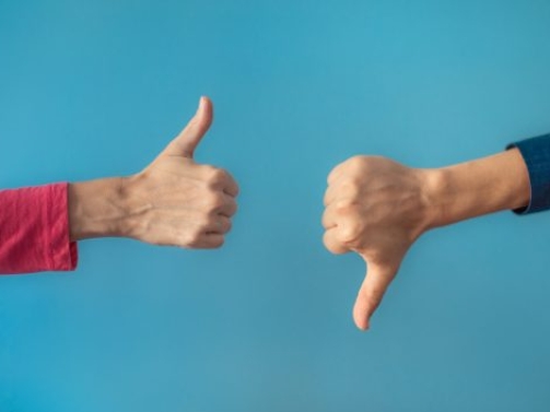 Two people making hand sign thumbs up and thumbs down.